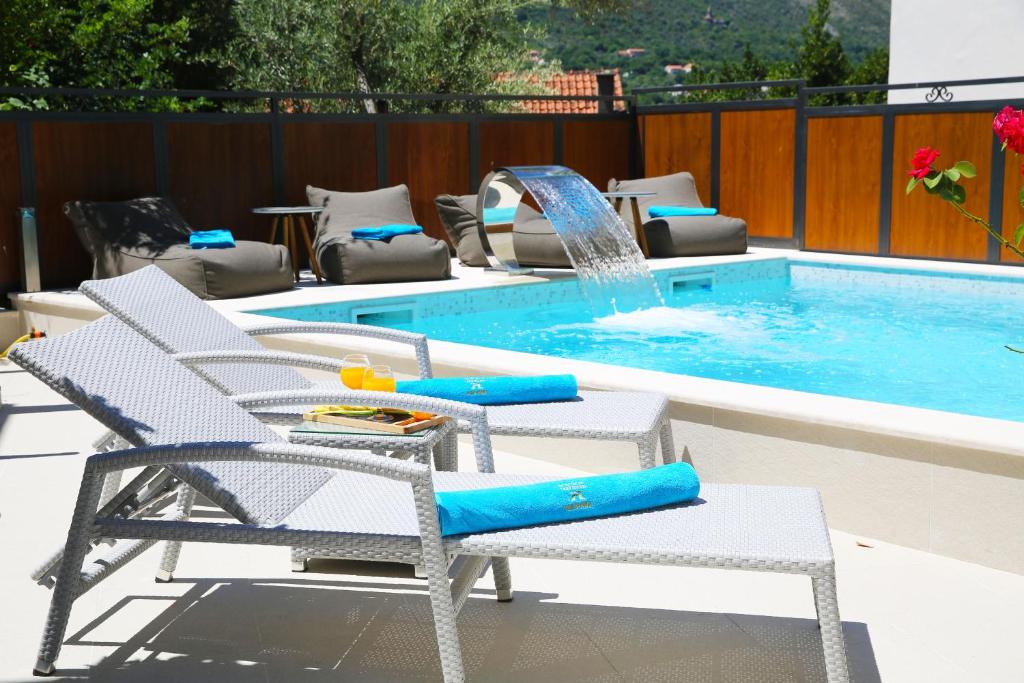 una piscina con 2 sillas y una fuente en Hotel Alkima en Kotor