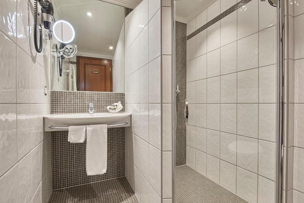 a white bathroom with a sink and a shower at Hotel d'Allèves in Geneva