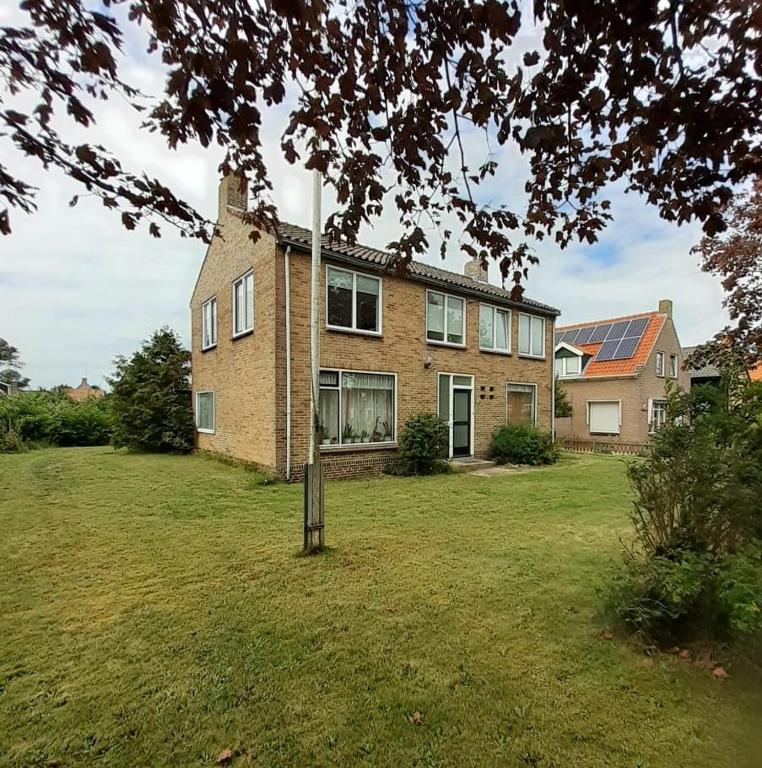 a large brick house with a grass yard at de Pastorie in Hollum