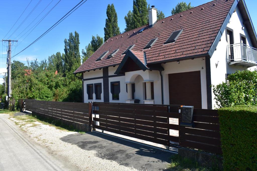 a house with a wooden fence next to a road at Sziget Vendégház in Szigliget