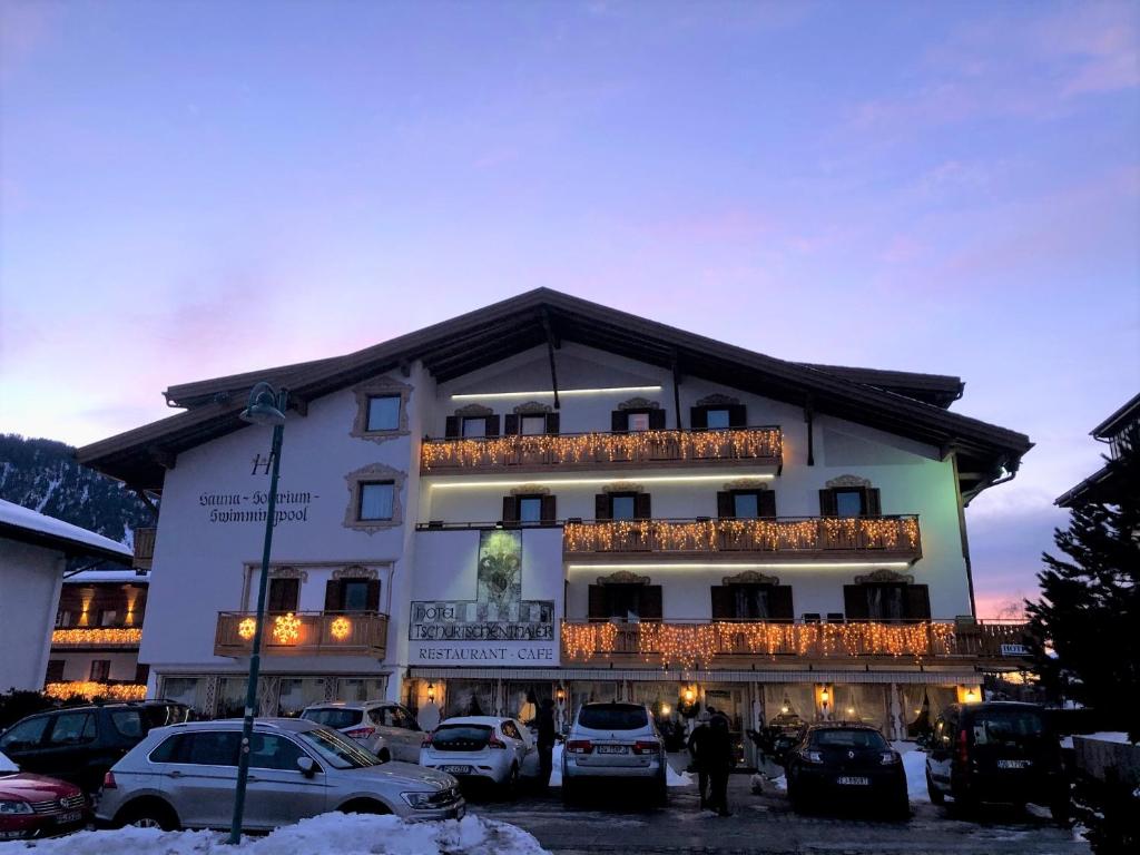 un gran edificio con coches estacionados frente a él en Hotel Tschurtschenthaler, en Dobbiaco