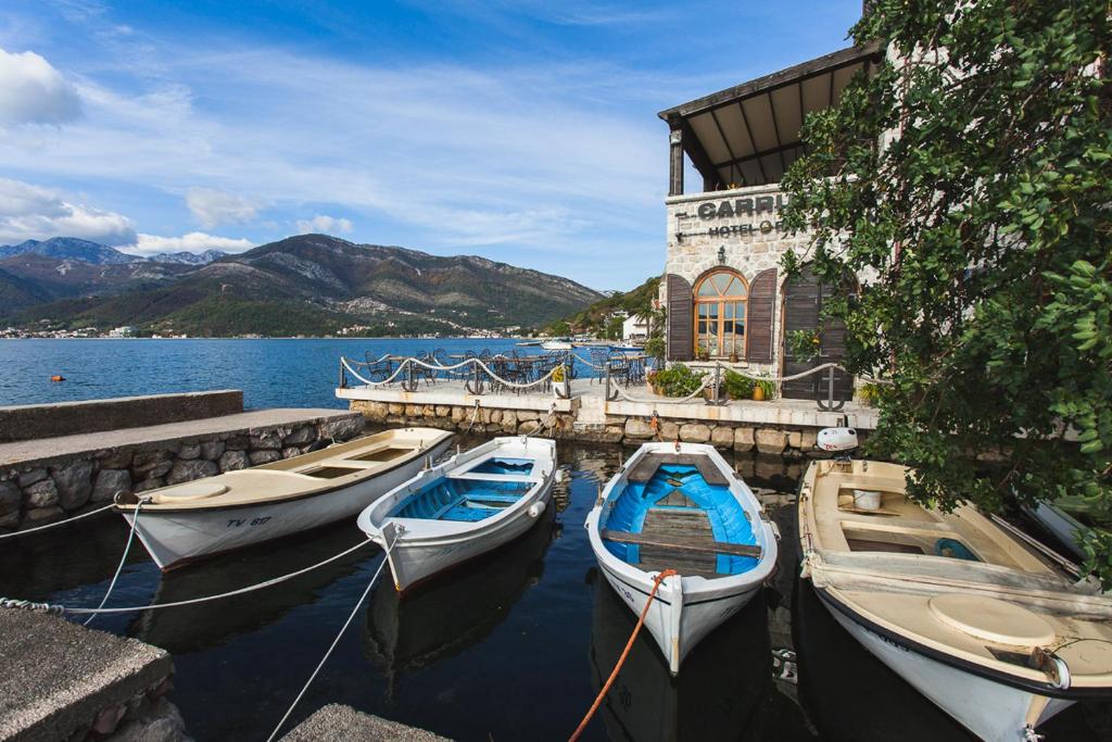 three boats are docked at a dock with a building at Eco Hotel Carrubba in Tivat