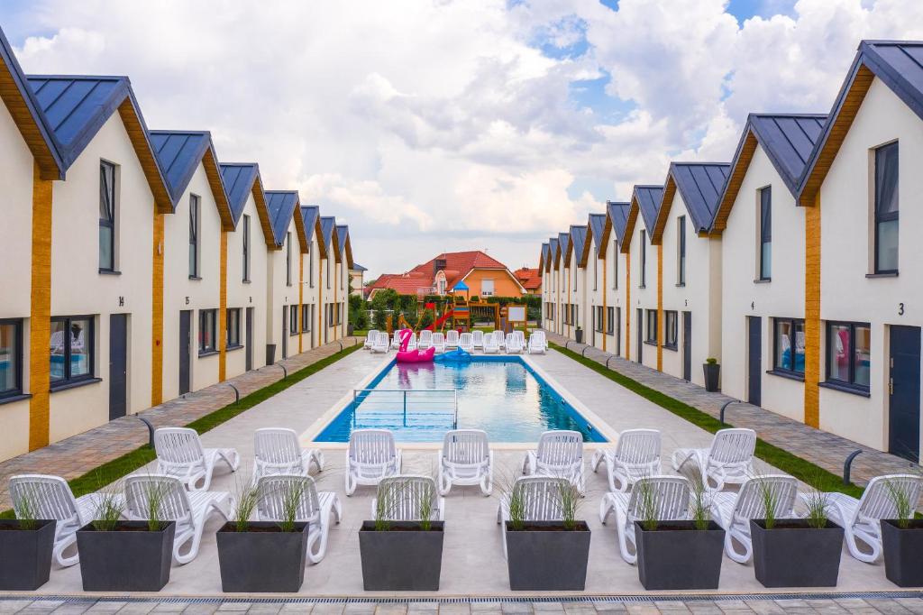 uma vista para uma piscina com cadeiras e edifícios em Amber Resort em Rewal
