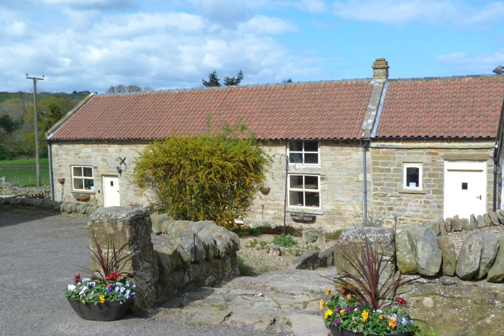 an old stone house with flowers in front of it at HayburnbeckFarm in Scarborough