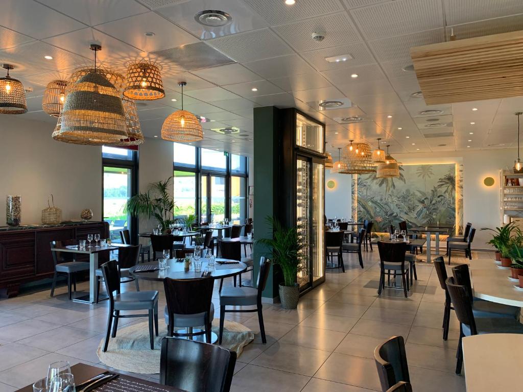 una sala da pranzo con tavoli, sedie e lampadari a braccio di Hôtel L'Horizon - Restaurant La Fougassette a Saint-Symphorien-sur-Coise