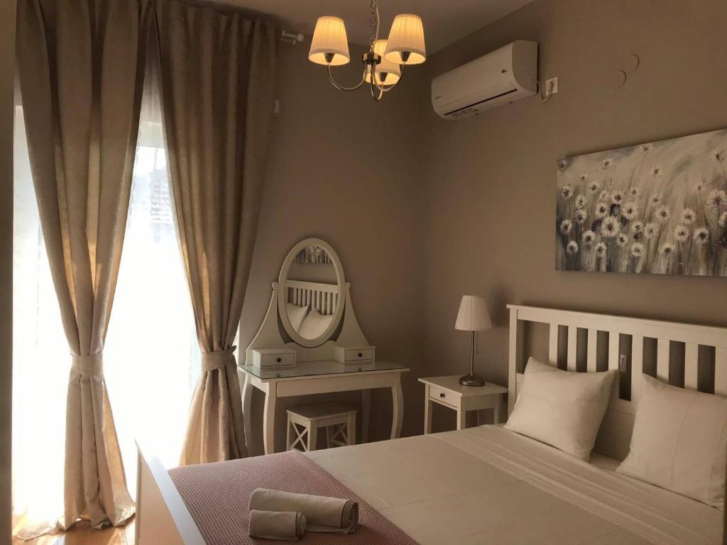 a bedroom with a white bed and a mirror at BALATSOURAS APARTMENT in Paleros