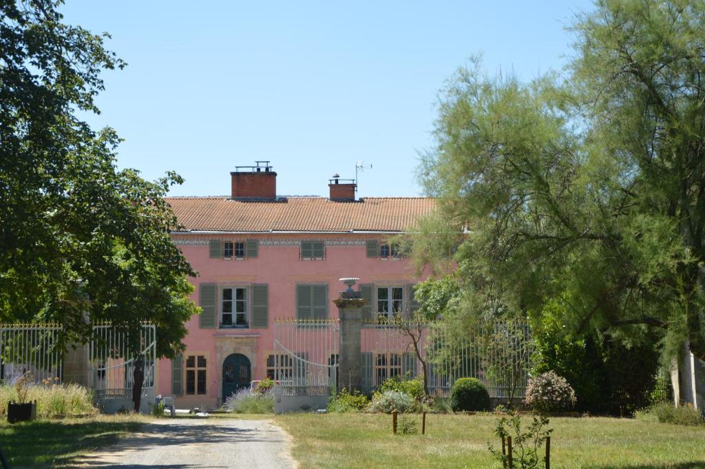un gran edificio rosa con una puerta y árboles en Domaine de Chalaniat, en La Sauvetat