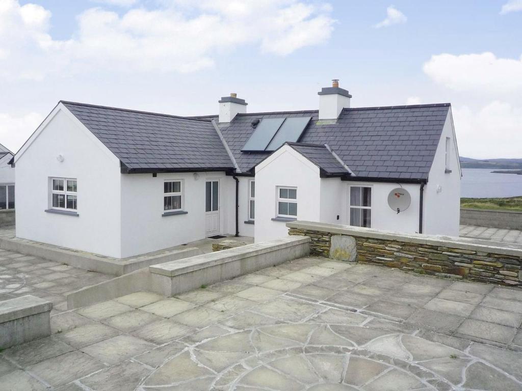 a white house with a stone patio in front of it at Timmys Cottage Heir Island by Trident Holiday Homes in Skibbereen