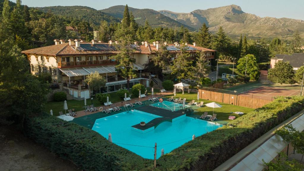 
a house that has a pool and some trees at Hotel Rural Spa & Wellness Hacienda Los Robles in Navacerrada
