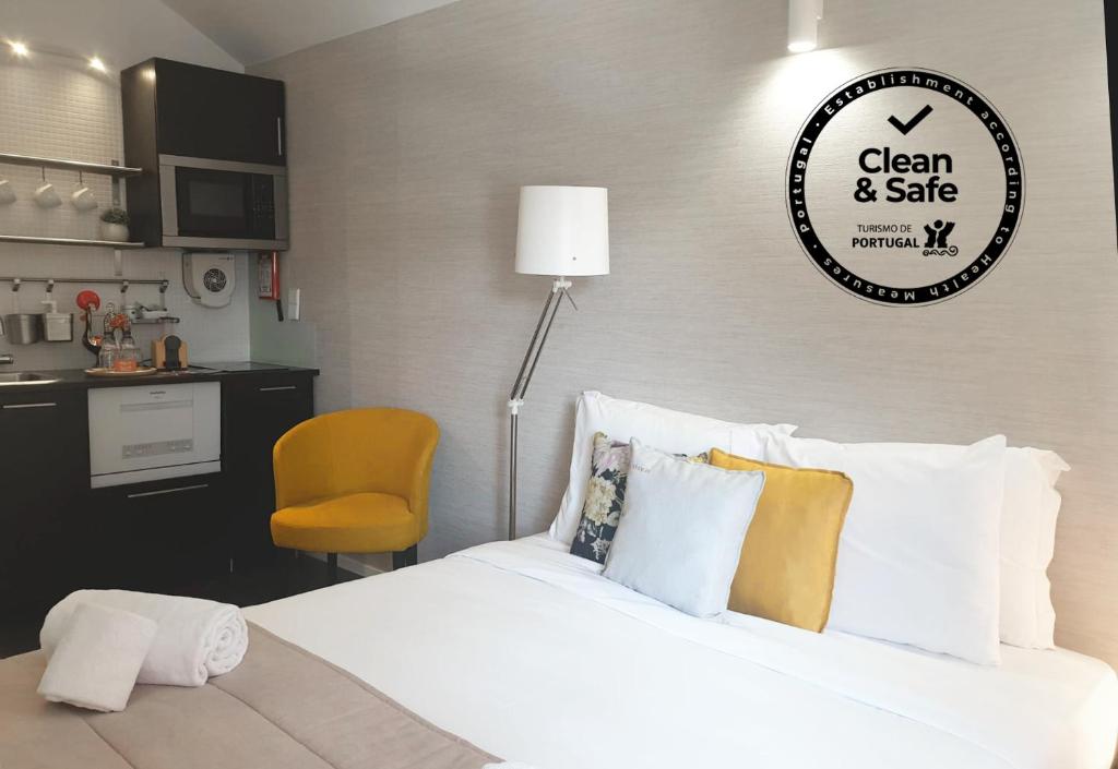 um quarto com uma cama branca e uma cadeira amarela em Stay in Apartments Ribeira 24 no Porto