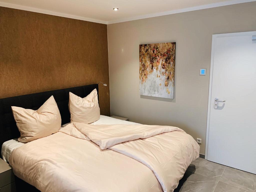 een slaapkamer met een bed met witte lakens en een schilderij bij OLÉ Hotel in Hamburg