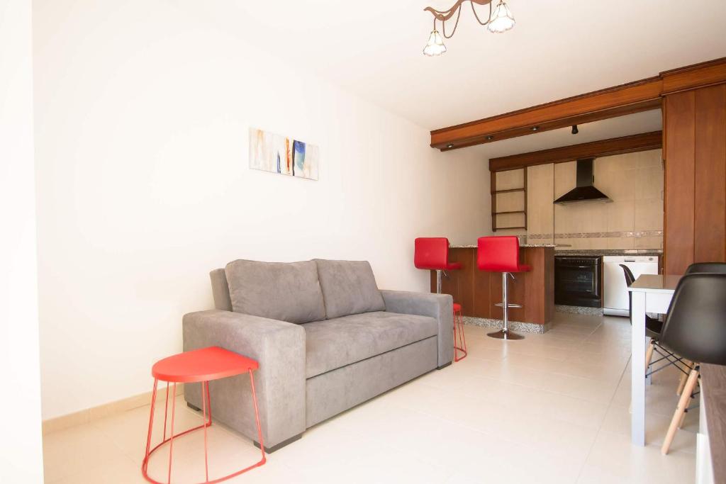 ein Wohnzimmer mit einem Sofa und zwei roten Hockern in der Unterkunft Los Molinos, con terraza in Corcubión