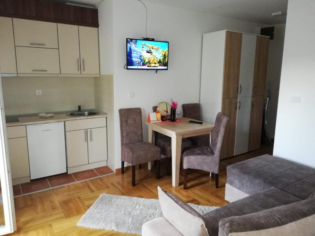 Vrnjačka BanjaにあるPremiumPlus Apartmanのキッチンとテーブルと椅子のあるリビングルーム