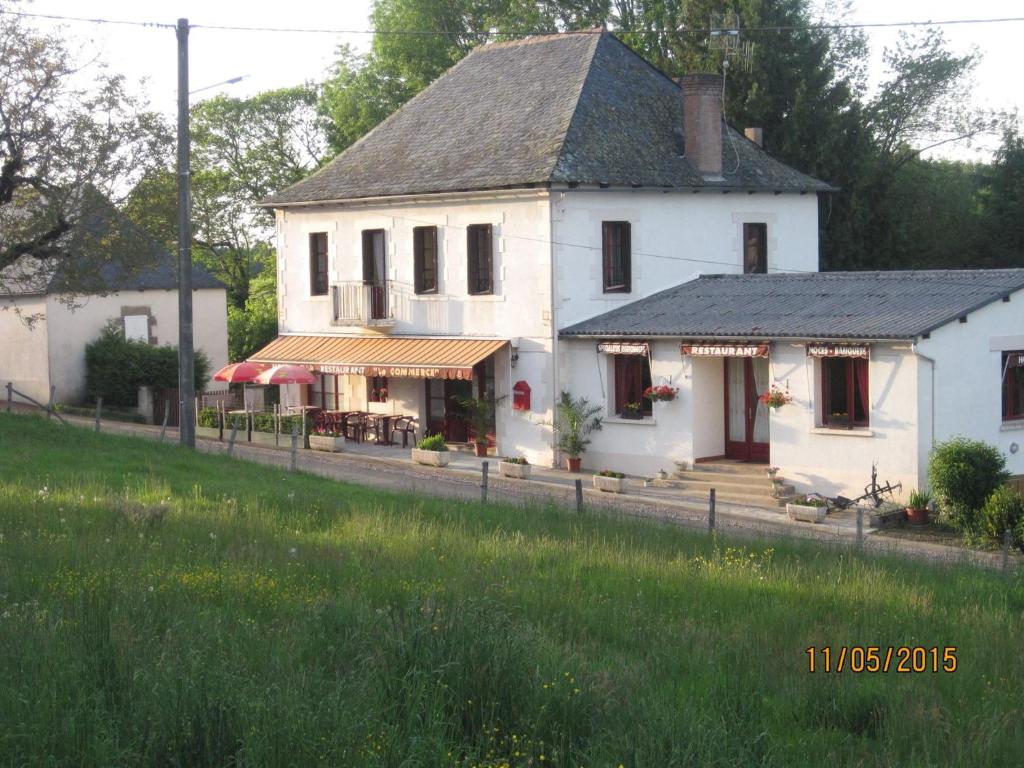 una casa blanca al lado de un campo en Hotel Le Commerce, en Neuville