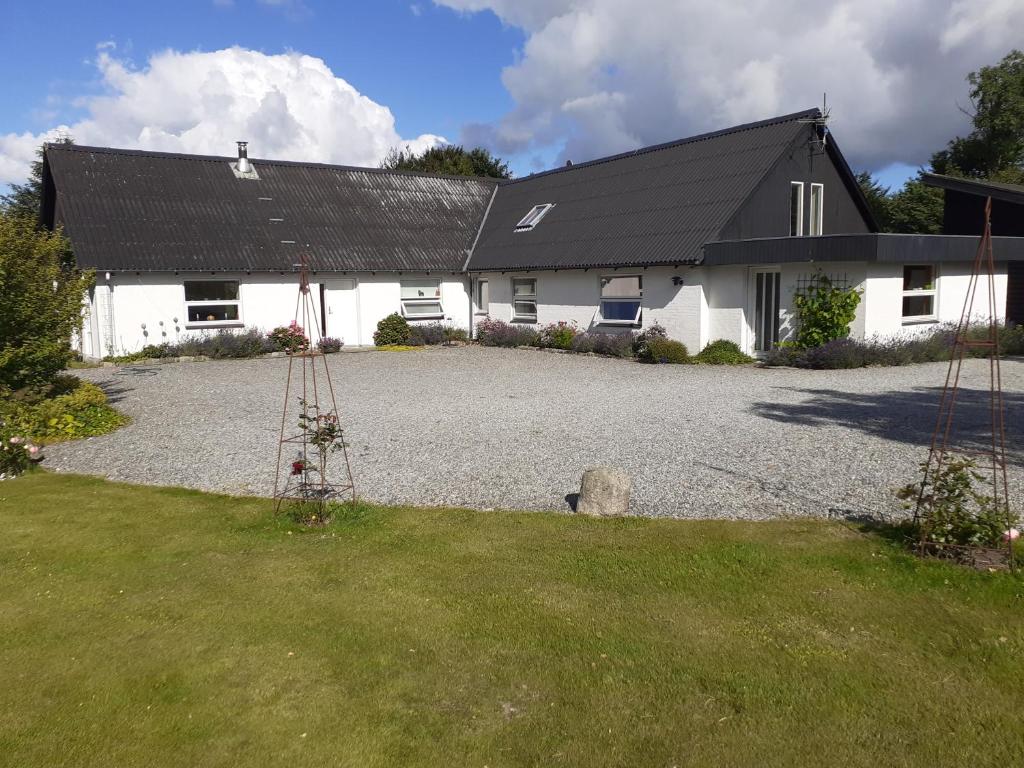 a white house with a black roof and a gravel driveway at Brovst bed and breakfast in Brovst