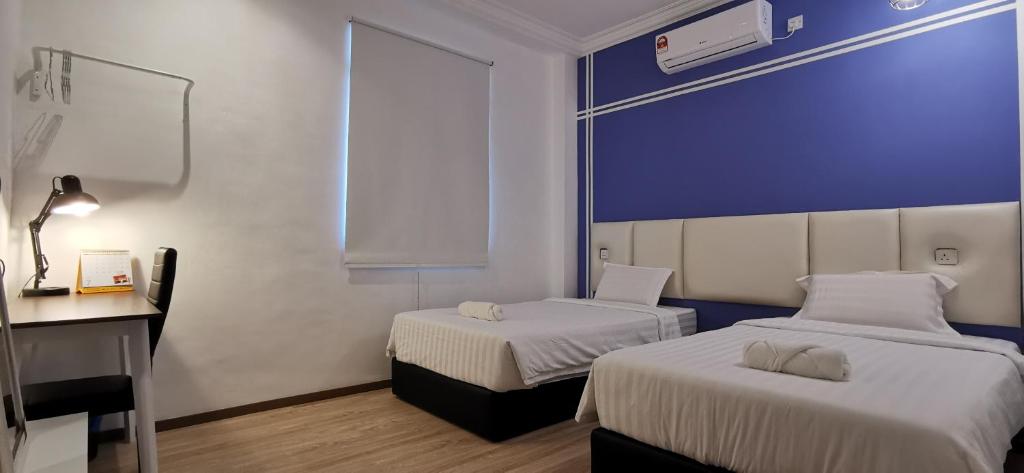 een kamer met 2 bedden en een bureau met een computer bij Foresight Hotel in Tawau