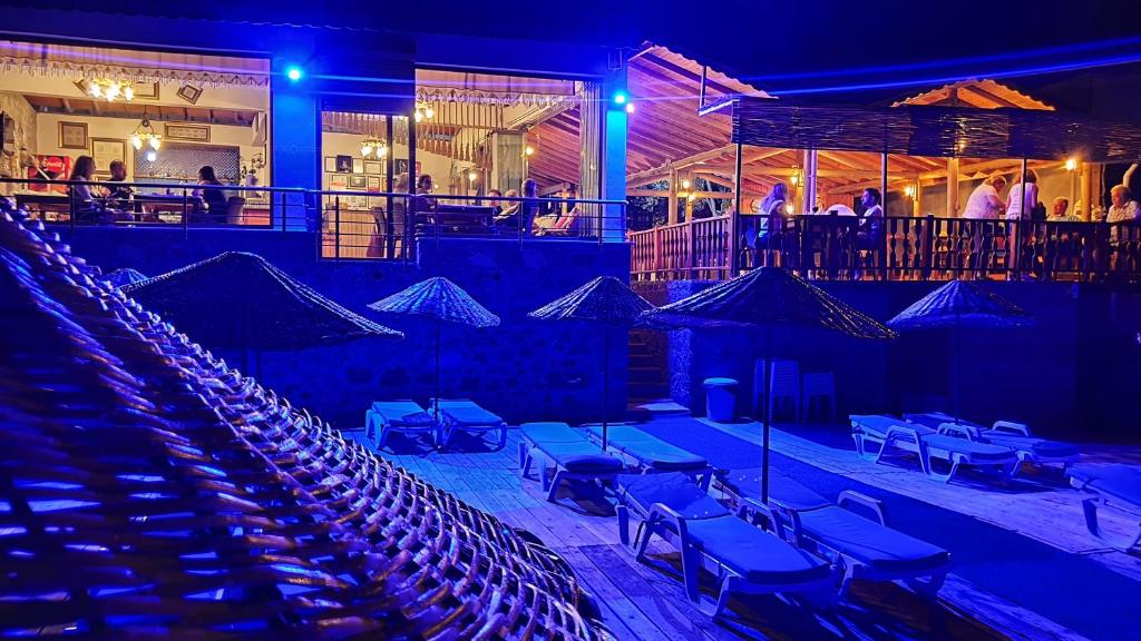 un groupe de chaises et de tables dans un théâtre la nuit dans l'établissement Assos Nazan Motel Restoran Beach, à Sokakagzi