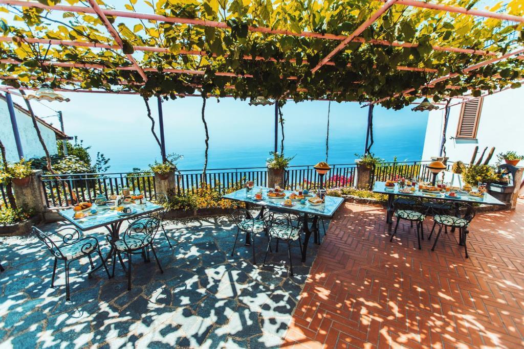 a patio with tables and chairs and the ocean at Roccia Fiorita in Furore