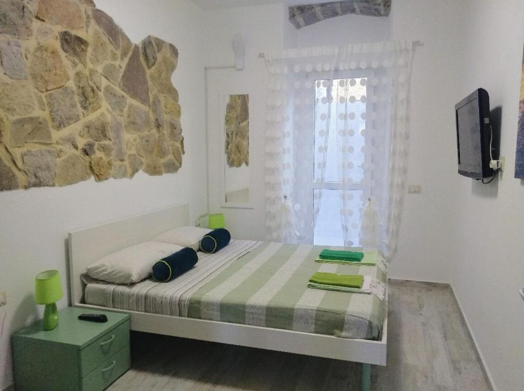 niewielka sypialnia z łóżkiem i oknem w obiekcie Green and Orange rooms w mieście Carloforte