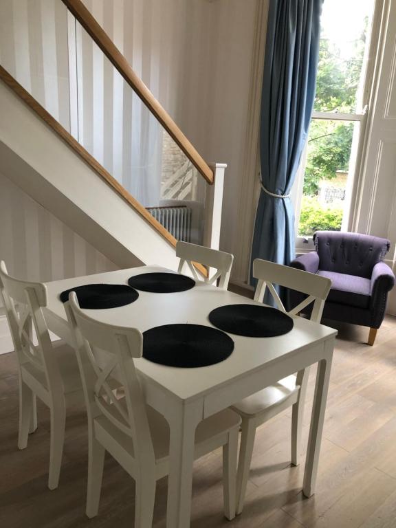 a white table and chairs in a living room at Elsham Apartments in London