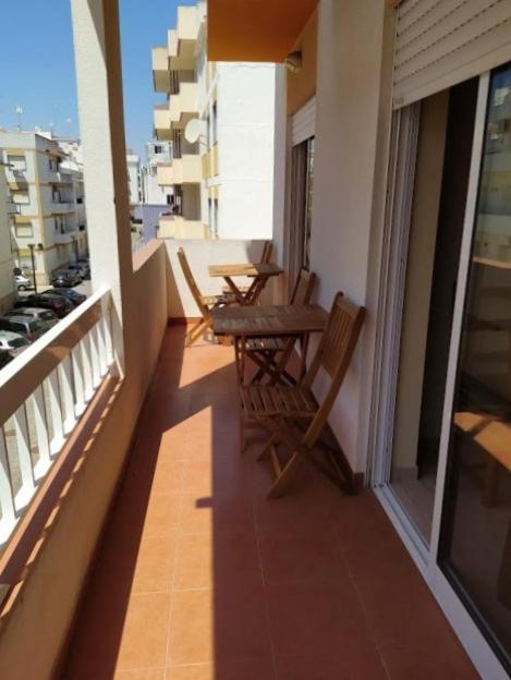 a balcony with two chairs and a table on a building at Beija Flor in Monte Gordo