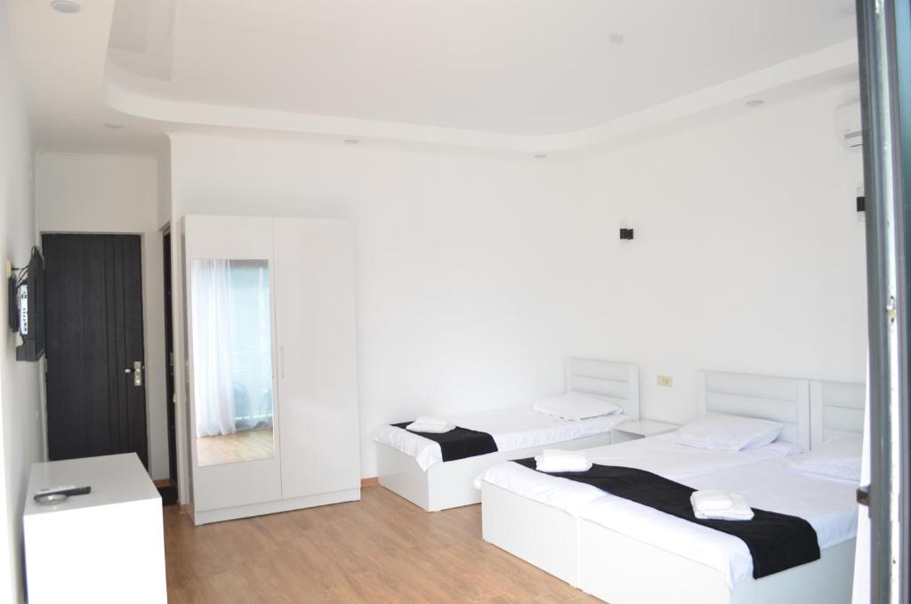 a white room with two beds and a mirror at White Hotel in K'obulet'i