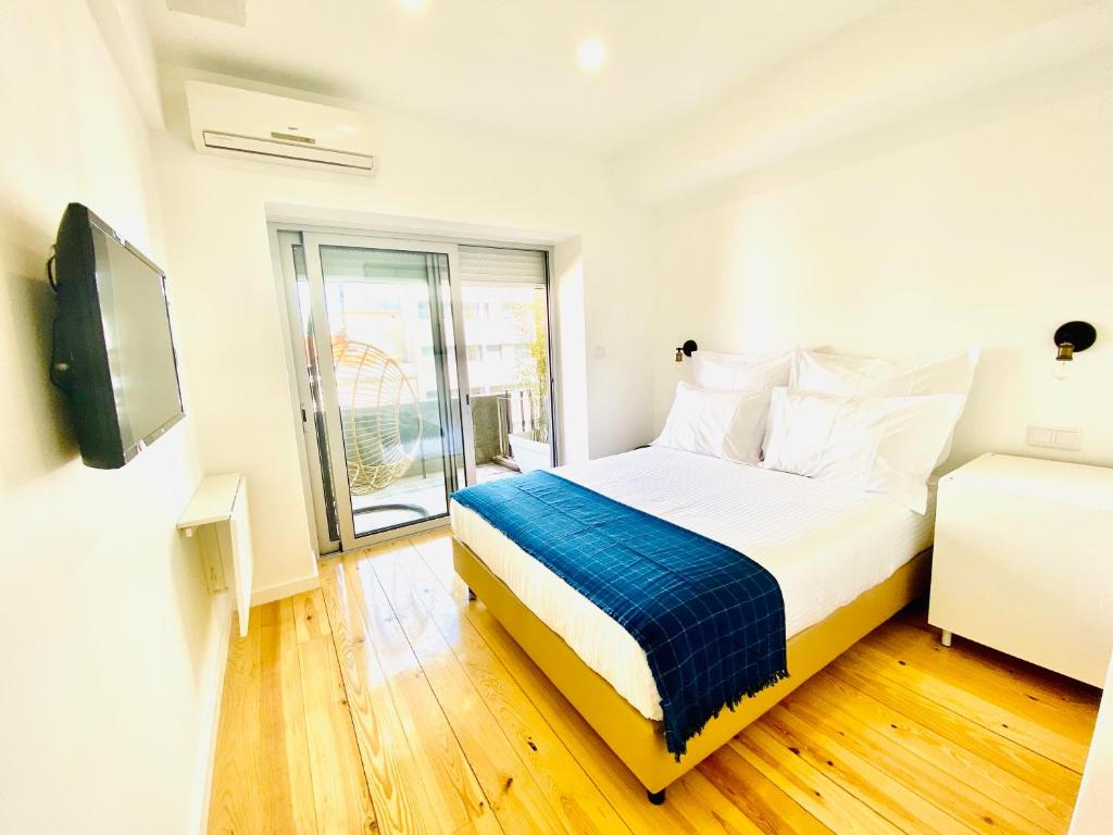 a white bedroom with a bed and a window at The Postcard Avenue in Lisbon