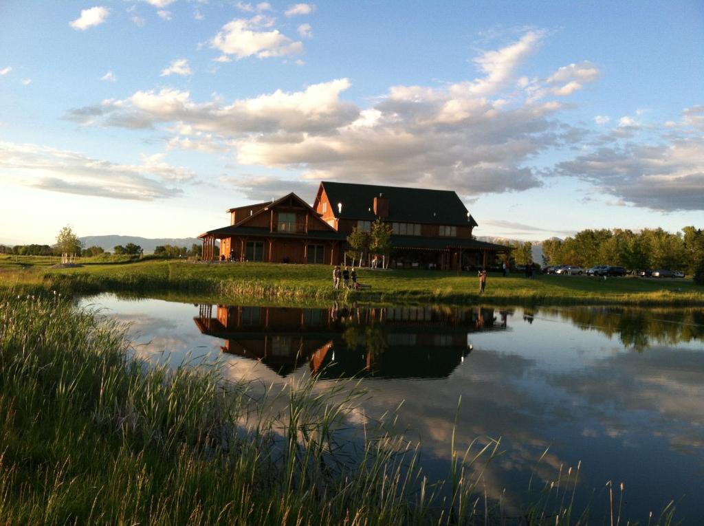 una casa junto a un lago con su reflejo en el agua en Gallatin River Lodge, en Bozeman