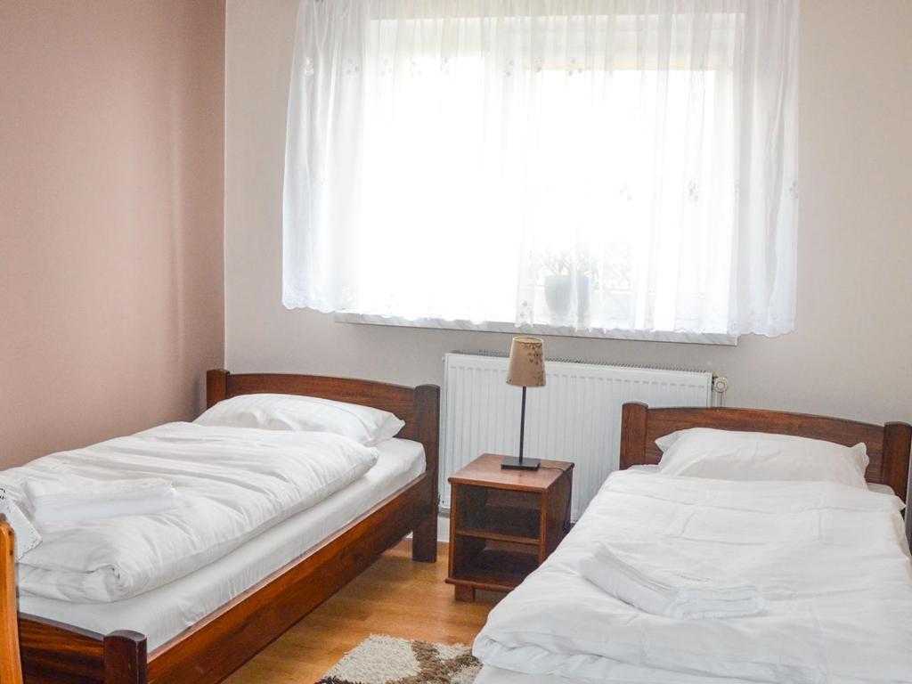 2 łóżka pojedyncze w pokoju z oknem w obiekcie Zamkowa Noclegi Restauracja w mieście Drohiczyn