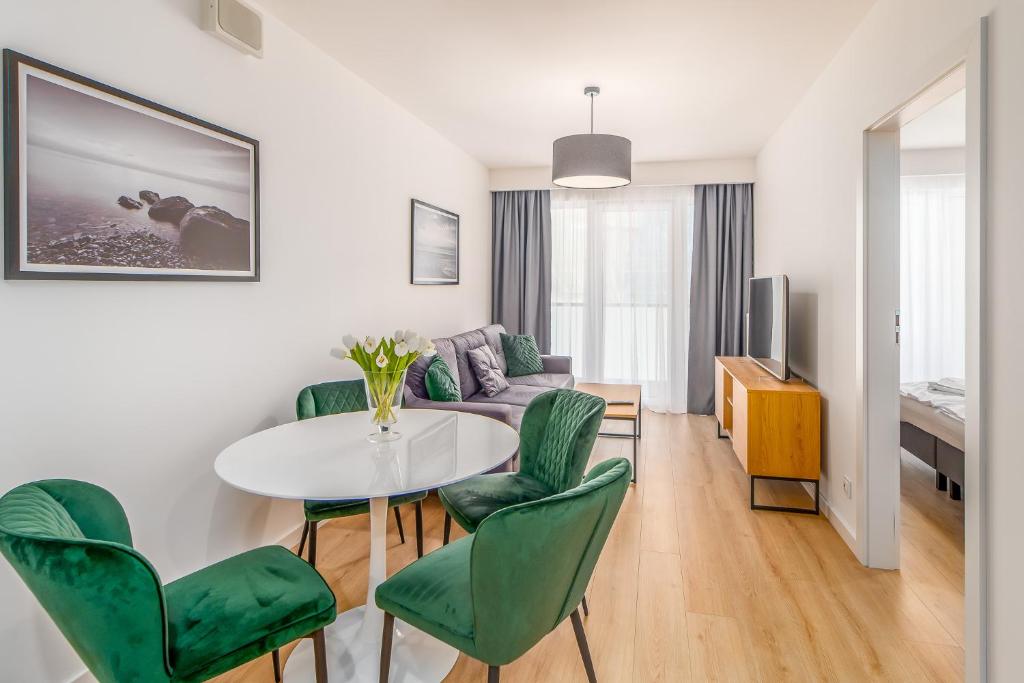 a living room with a table and green chairs at FARO Apartamenty Kasprowicza 20 in Kołobrzeg