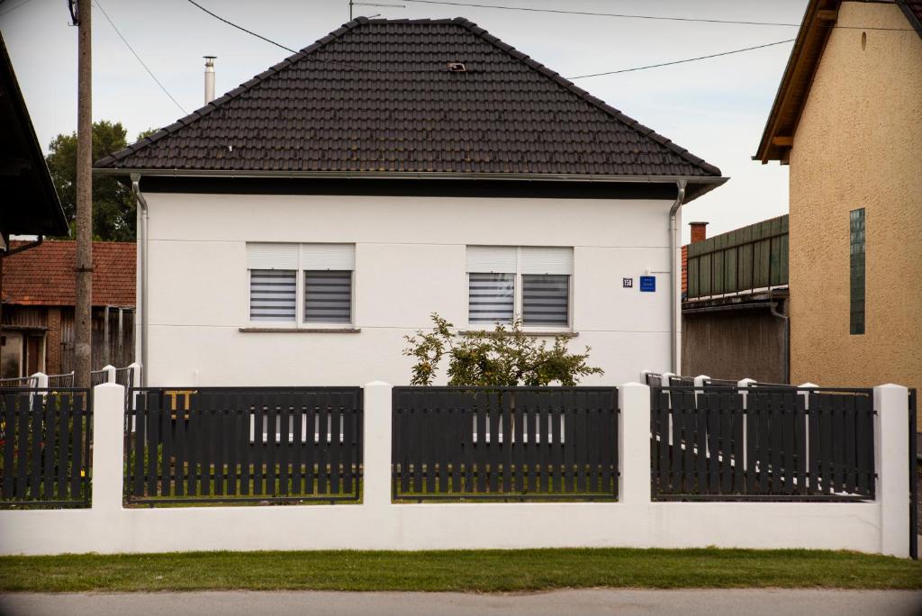 una casa blanca con una valla negra en Apartman Kuća 150, en Mala Subotica