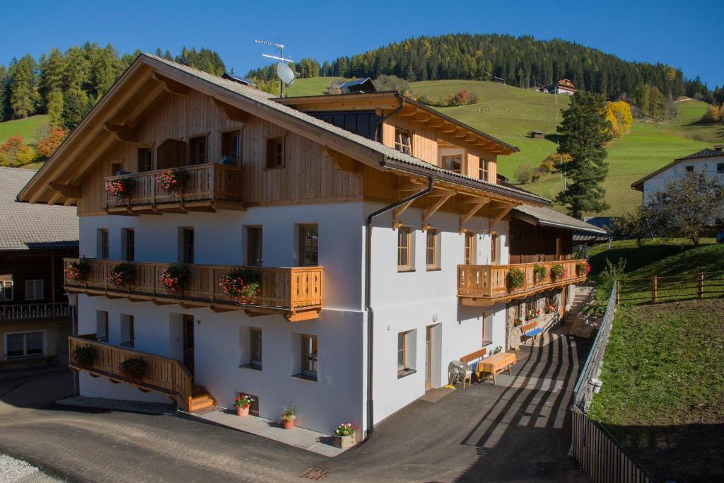 a large white building with balconies on a hill at Appartments Jagerhof in Braies