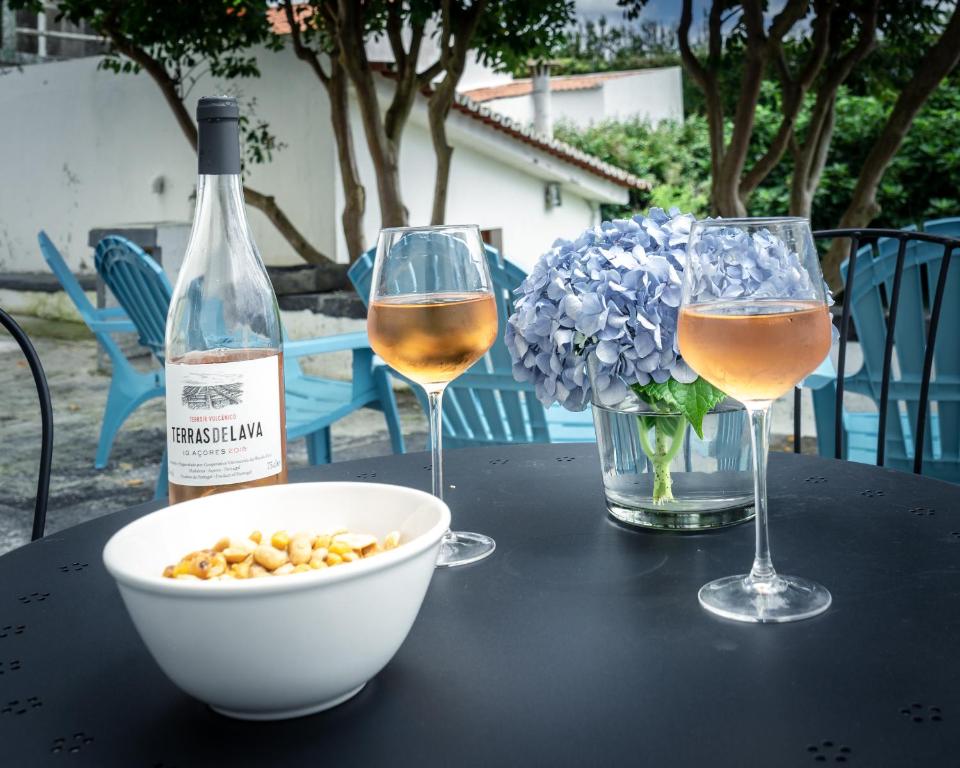 una mesa con dos copas de vino y un tazón de nueces en city center, 200 meters to marina, walk to everything, private yard and garden, en Ponta Delgada