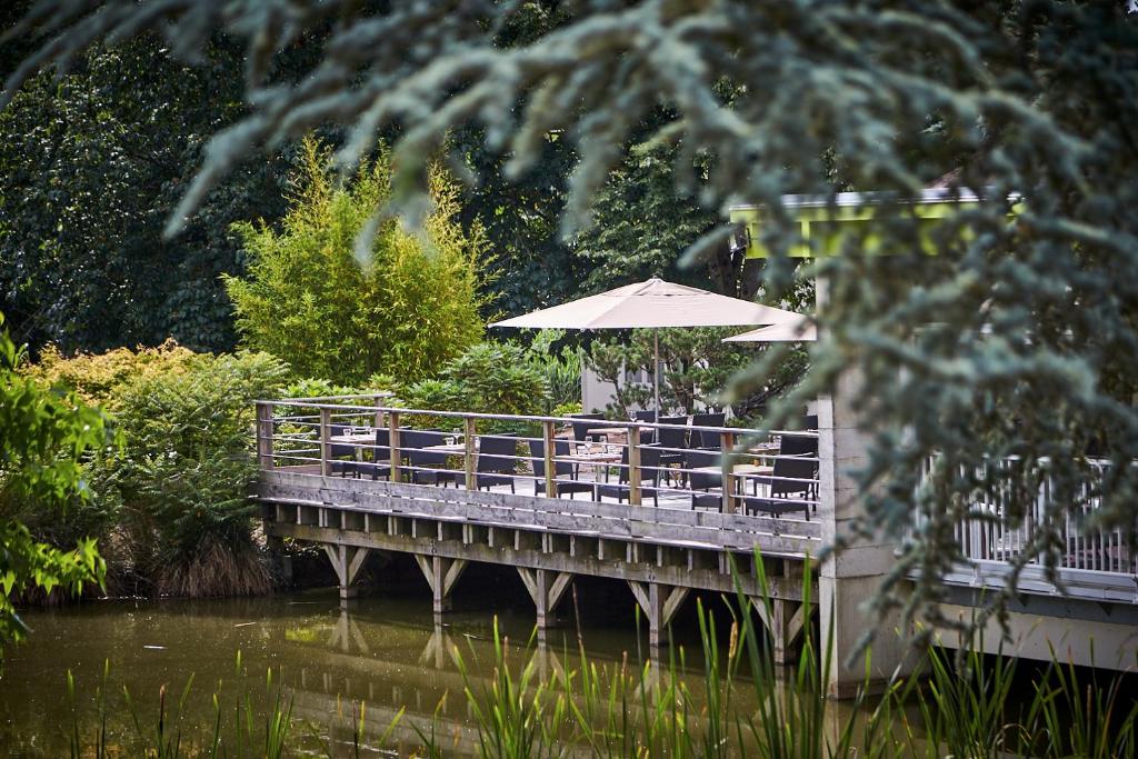 un pont avec une table et un parasol dans l'établissement Les Jardins de l'Anjou, à La Pommeraye