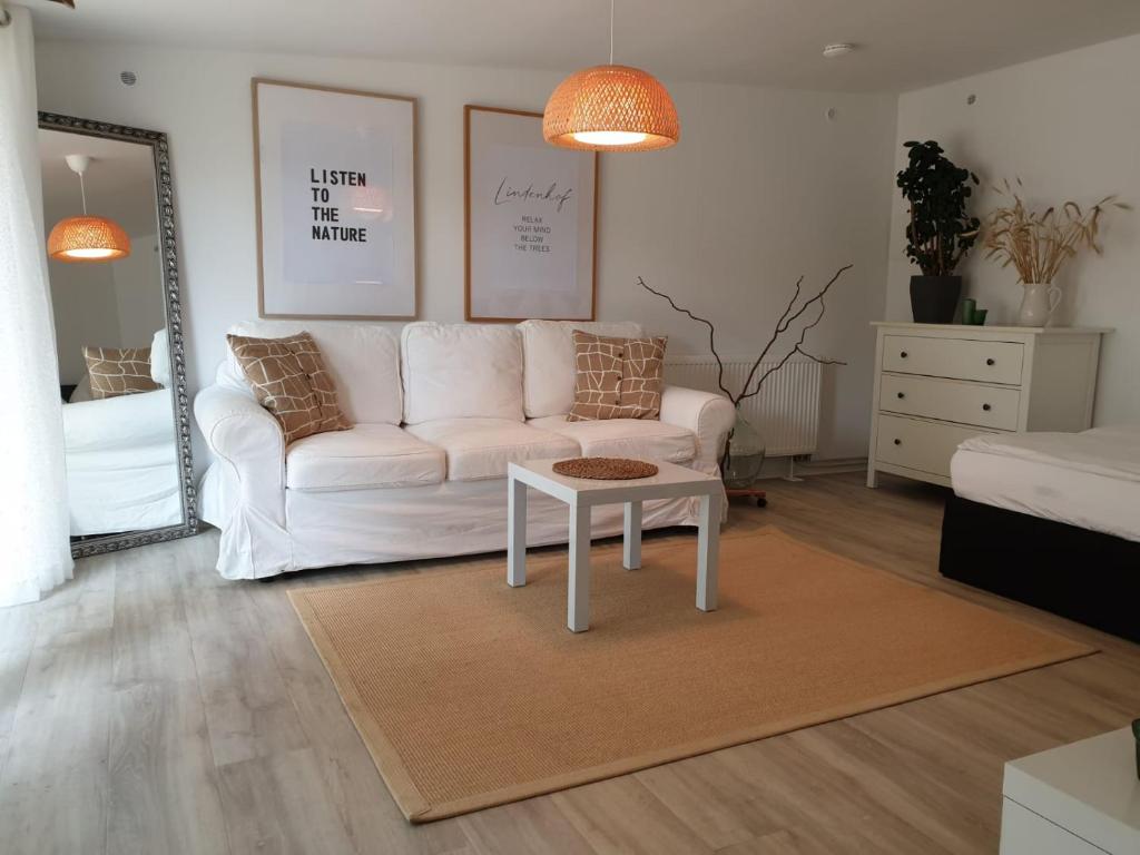 ein Wohnzimmer mit einem weißen Sofa und einem Tisch in der Unterkunft Ferienwohnung Lindenhof, zentrumsnah mit Terrasse und Grillmöglichkeit in Magdeburg