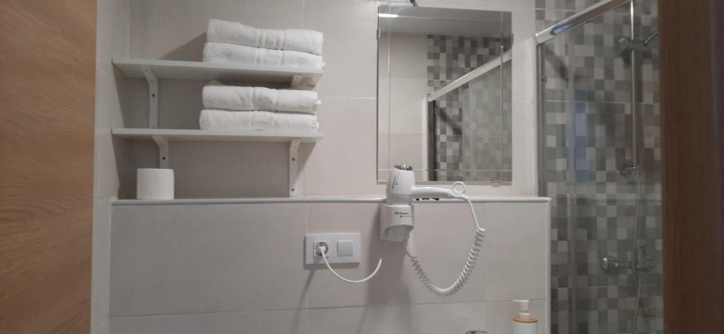 bagno con asciugamani e telefono appeso al muro di Pensión CASA LEÓN a Santoña