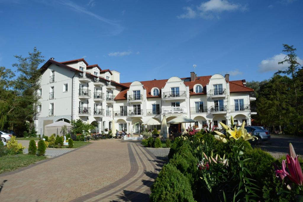 a large white building with a red roof at Dworek Jamneński in Łazy