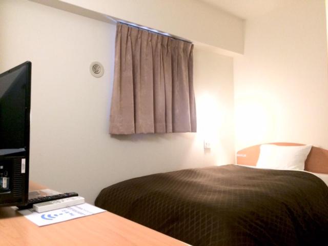 a bedroom with a bed and a desk with a computer at Anchor Hotel Hakata in Fukuoka