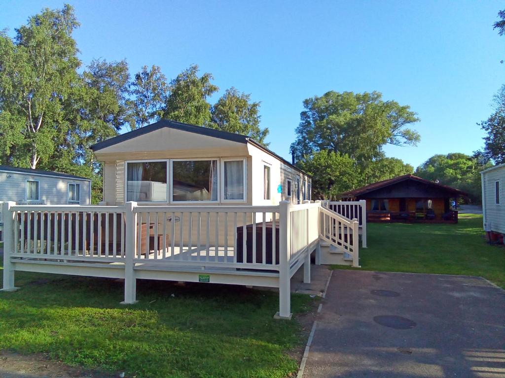 een klein wit huis met een veranda op het gras bij Beautiful 3 bedroom caravan with hot tub - Tattershall Lakes in Tattershall