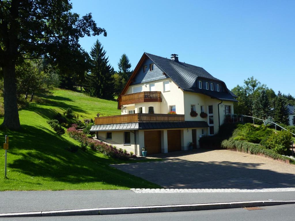 a white house with a black roof on a hill at Ferienwohnung Cafe`Rotter , Brigitte und Jürgen Rotter in Schellerhau