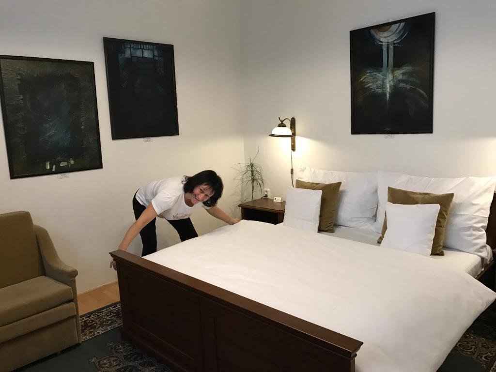 a woman standing next to a bed in a room at Antik Hotel Sofia in Litomyšl