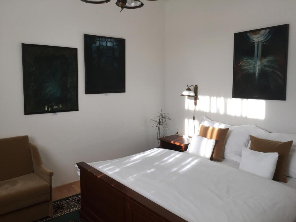 a bedroom with a large white bed and a chair at Antik Hotel Sofia in Litomyšl