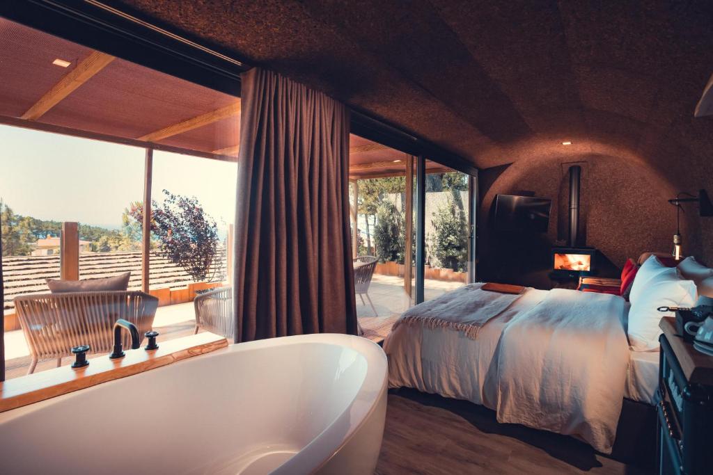 a bathroom with a tub and a bed and a bedroom at Charm Nature in Azoia