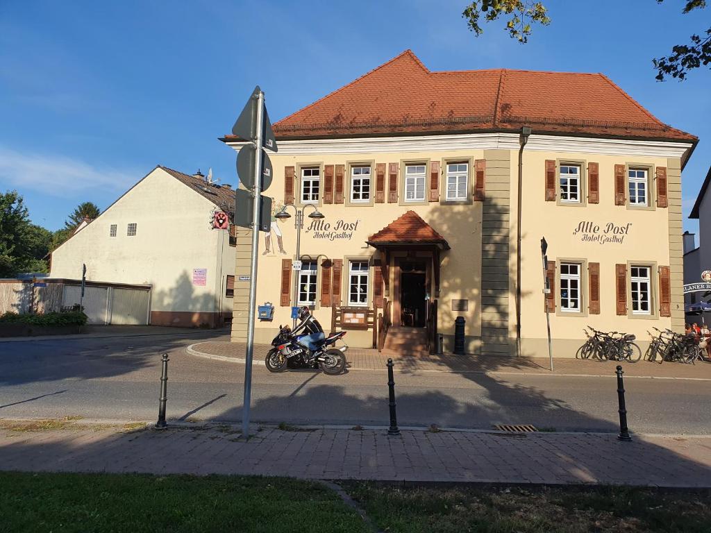 Gasthof Alte Post في رينهاوسن: رجل على دراجة نارية أمام المبنى