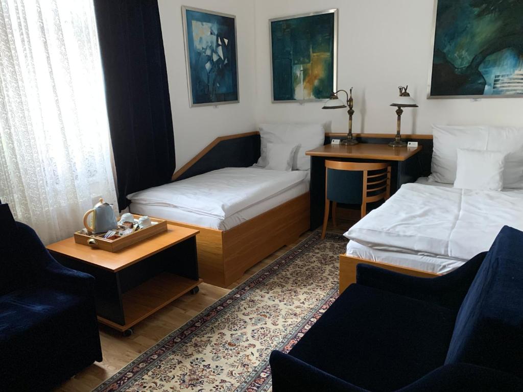 a room with two beds and a table and a couch at Antik Hotel Sofia in Litomyšl