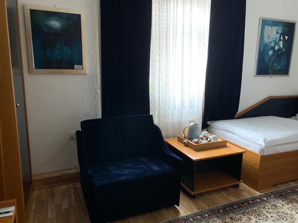 a bedroom with a bed and a chair and a table at Antik Hotel Sofia in Litomyšl