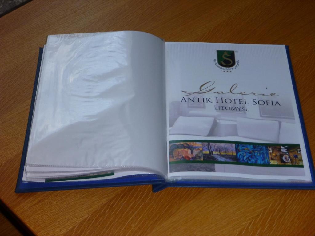an open book with a pen on top of a table at Antik Hotel Sofia in Litomyšl