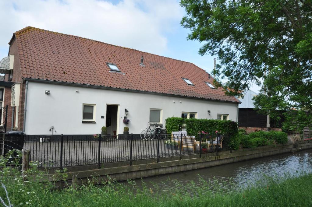 een wit huis met een rood dak naast een rivier bij Johannahoeve in Utrecht