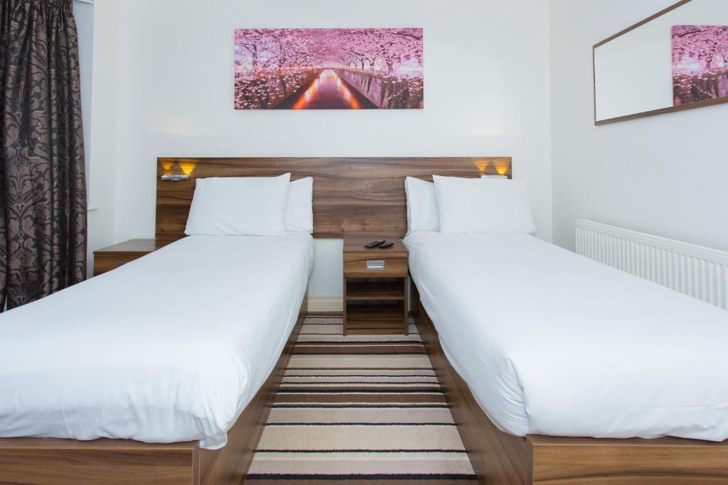 2 camas en una habitación con sábanas blancas en Langley Guest House, en Slough