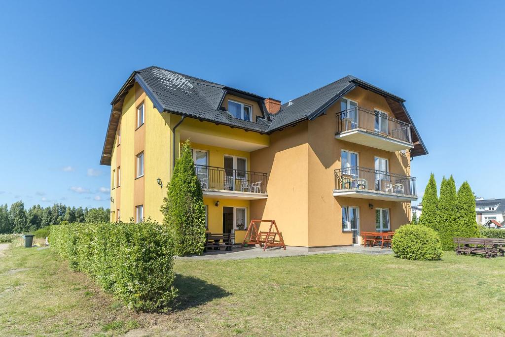 a large yellow house with a black roof at Pokoje gościnne Neptun in Ostrowo